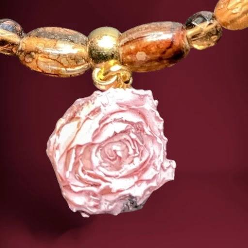 Heartfelt Creations design of a vintage-style jewelry set consisting of a necklace, bracelet, and earrings, all featuring a mix of translucent amber-colored glass beads and opaque pale pink beads, with the necklace having a large, carved pink rose pendant and the earrings being a dangling design with a single amber and pink bead.