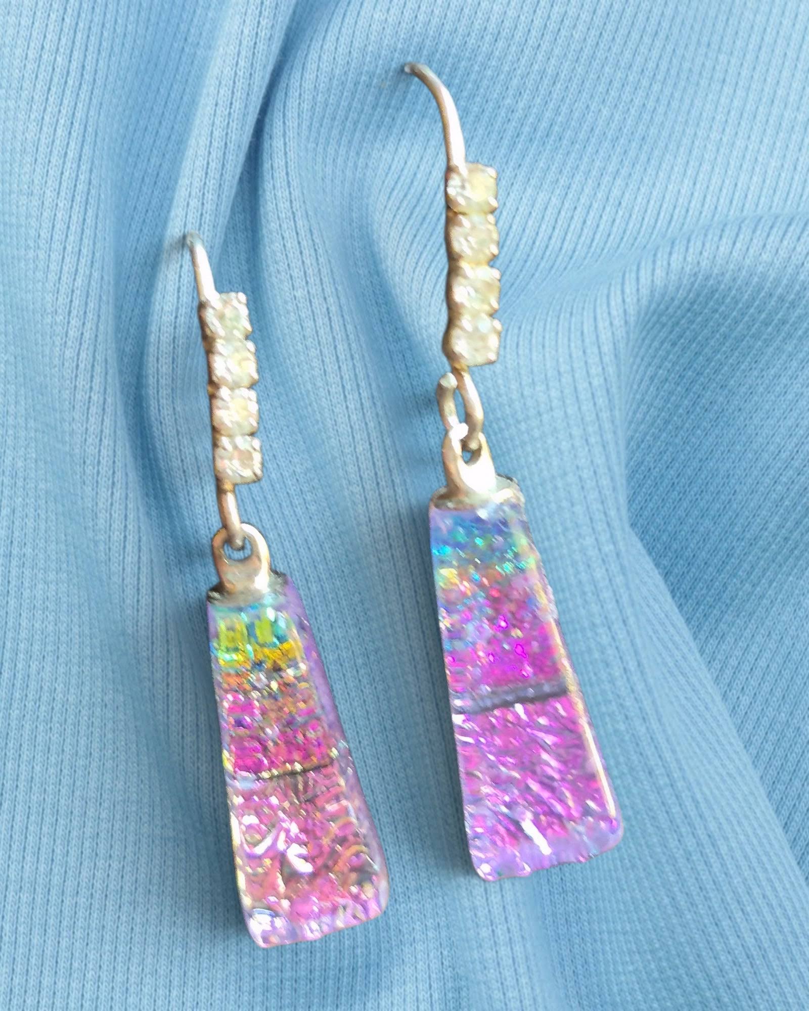 Multicolored teardrop earrings on a blue fabric background