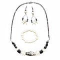 Heartfelt Creations offers a uniquely designed  jewelry set featuring a necklace, matching earrings, and a bracelet. The necklace includes black stones, white ivory-like beads, and a central black/white/grey marbled focal bead on the necklace.  A gun metal chain completes the necklace.  Finally, a simple yet striking bracelet with carved beads and drop earrings offering all the features, completes the set,