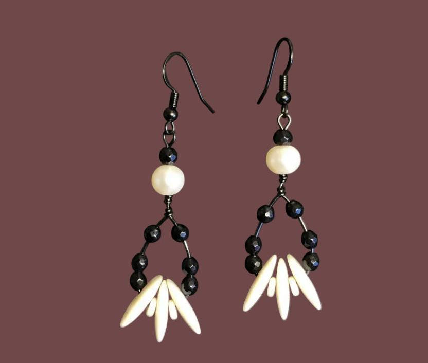 Heartfelt Creations offers a uniquely designed  jewelry set featuring a necklace, matching earrings, and a bracelet. The necklace includes black stones, white ivory-like beads, and a central black/white/grey marbled focal bead on the necklace.  A gun metal chain completes the necklace.  Finally, a simple yet striking bracelet with carved beads and drop earrings offering all the features, completes the set,