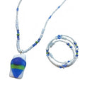 Heartfelt Creations' handmade jewelry set featuring a necklace and a multi-strand bracelet, both crafted with a mix of small, round, white, blue, and green beads, with the necklace featuring a prominent, rectangular, fused glass pendant with a vibrant blue, green, and white abstract design.