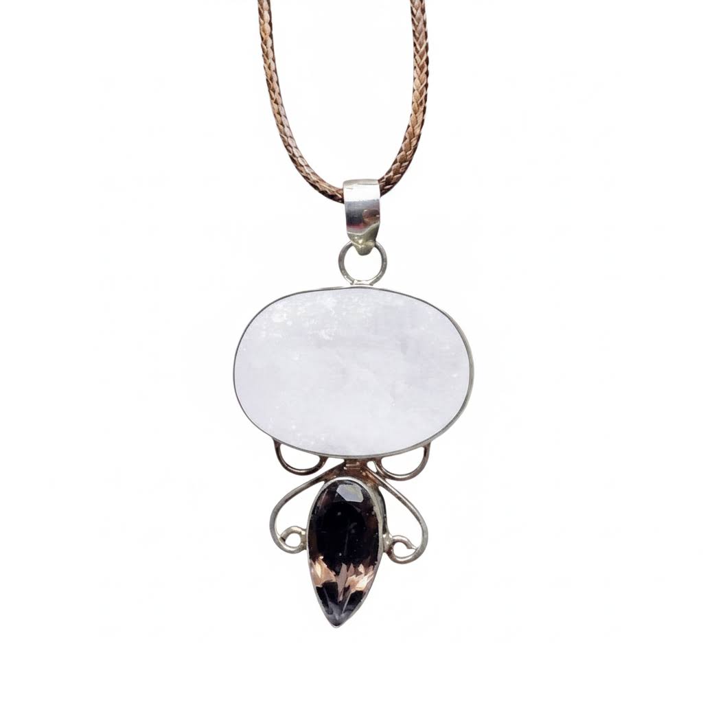 a handmade sterling silver pendant featuring a large, oval-shaped white moonstone cabochon and a smaller, teardrop-shaped faceted smoky quartz gemstone, connected by intricate silver wire scrollwork, suspended from a braided brown leather cord.