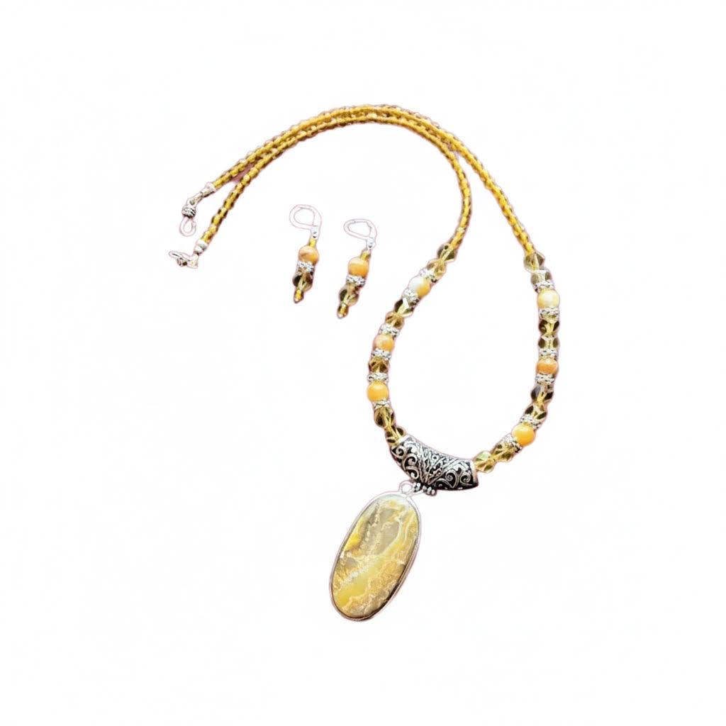 Heartfelt Creations' handcrafted jewelry set featuring a  Bumblebee Jasper and 925 silver plated pendant necklace and matching earrings.  The necklace is composed of small, faceted yellow and orange beads, a large oval-shaped, polished stone pendant with a yellow and white marbled pattern, and a decorative, ornate silver-toned metal clasp, and the earrings consisting of a single yellow bead and a smaller, matching orange bead on a silver-toned hook.