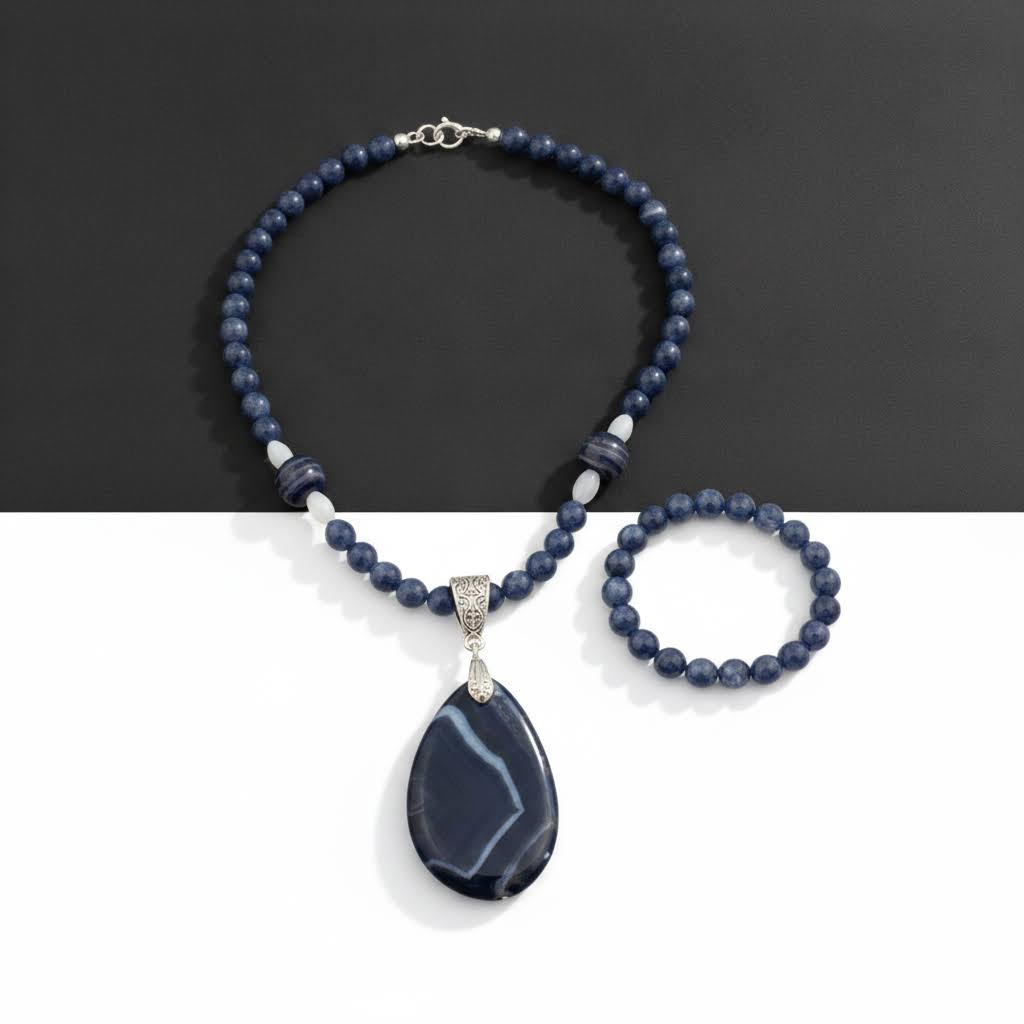 a handmade jewelry set featuring a necklace and bracelet, both crafted from polished, deep blue and white striped agate beads, with the necklace having a large, teardrop-shaped agate pendant suspended from a detailed silver bail, and the bracelet being a single strand of matching beads.