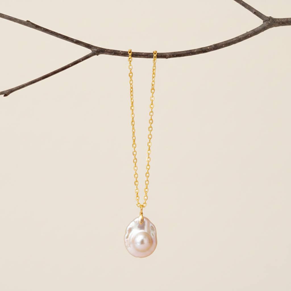Heartfelt Creations is delighted to offer gold chain necklace featuring a large, organic-shaped pearl pendant from the shores of New Zealand!  It radiates with iridescent white, pink, and green hues, displayed with a golden chain.