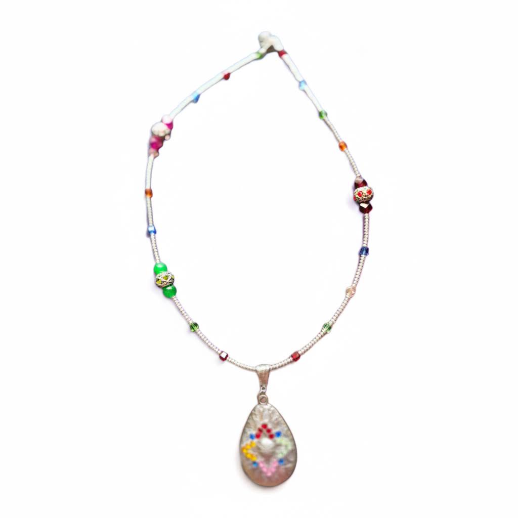 a delicate, handmade necklace featuring a thin, silver-toned chain adorned with small, multi-colored glass beads, leading to a teardrop-shaped pendant with a mosaic-like pattern of tiny, vibrant stones.
