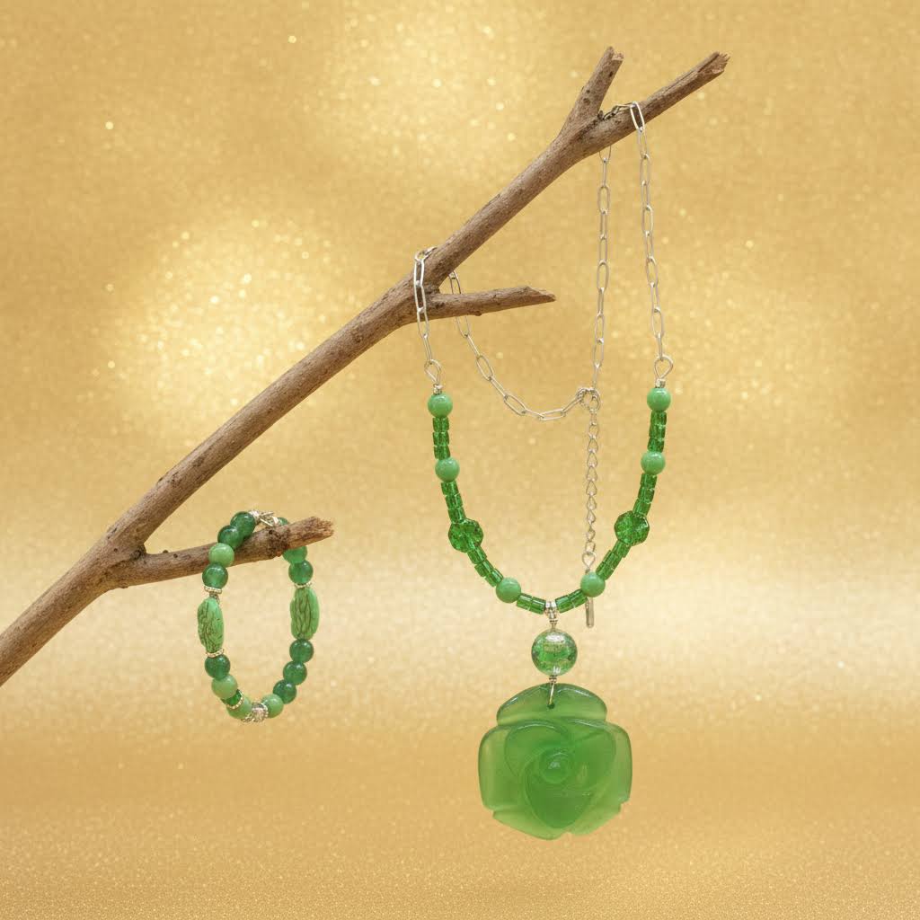 Heartfelt Creations' offers this stunning, nature-inspired beaded necklace and bracelet set. Featuring a vibrant palette of lush greens, this set is designed to add a touch of botanical elegance to any outfit. The centerpiece of the necklace is a beautifully detailed, frosted glass floral charm that captures the essence of a blooming rose, complemented by a variety of green beads that offer a rich, multi-textured look. The matching bracelet echoes this design, creating a cohesive and polished aesthetic.