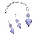 Heartfelt Creations offers a matching set of handcrafted jewelry, including a necklace and a pair of earrings, featuring silver-toned chains and hooks, with each piece adorned with a pale pink, swirled lampwork  glass heart bead and a delicate, clear glass flower bead.