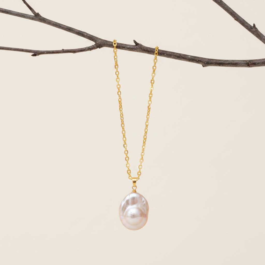 Heartfelt Creations is delighted to offer gold chain necklace featuring a large, organic-shaped pearl pendant from the shores of New Zealand!  It radiates with iridescent white, pink, and green hues, displayed with a golden chain.